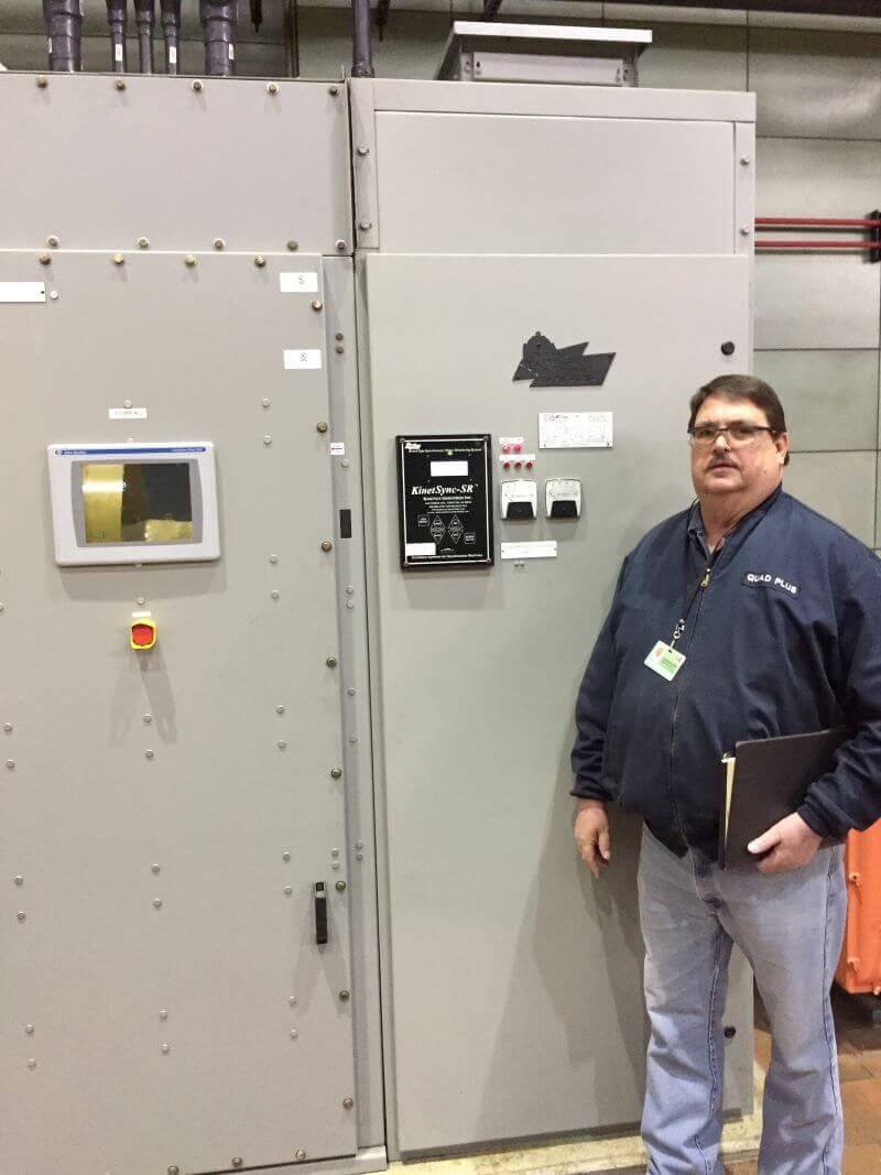 technician beside a synchronous electric motor system panel