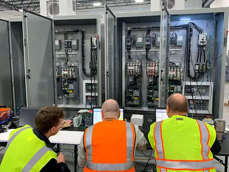 industrial machine repair team working on control panels